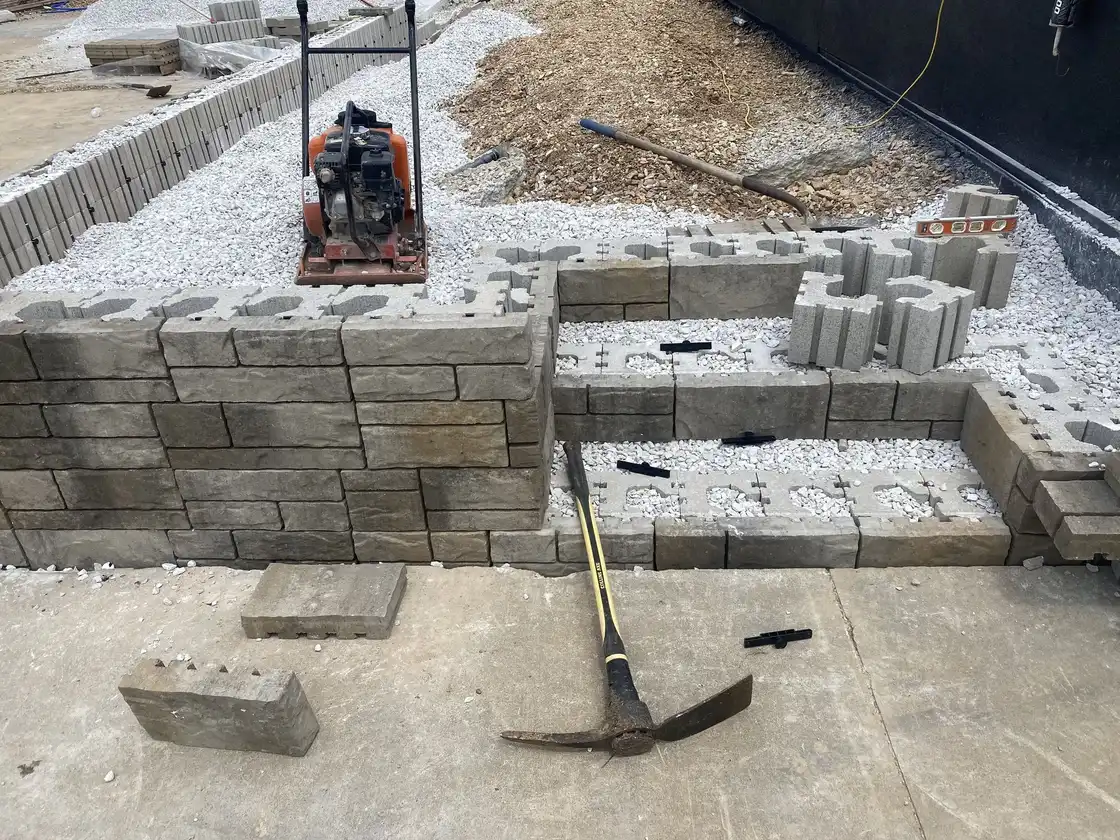 A block wall and steps going in, with the plate compactor on the gravel, one of our jobs