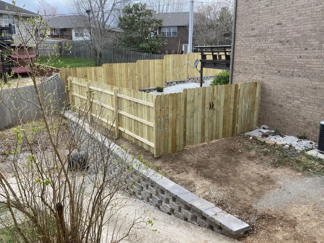 A block retaining wall below a new privacy fence, one of our jobs