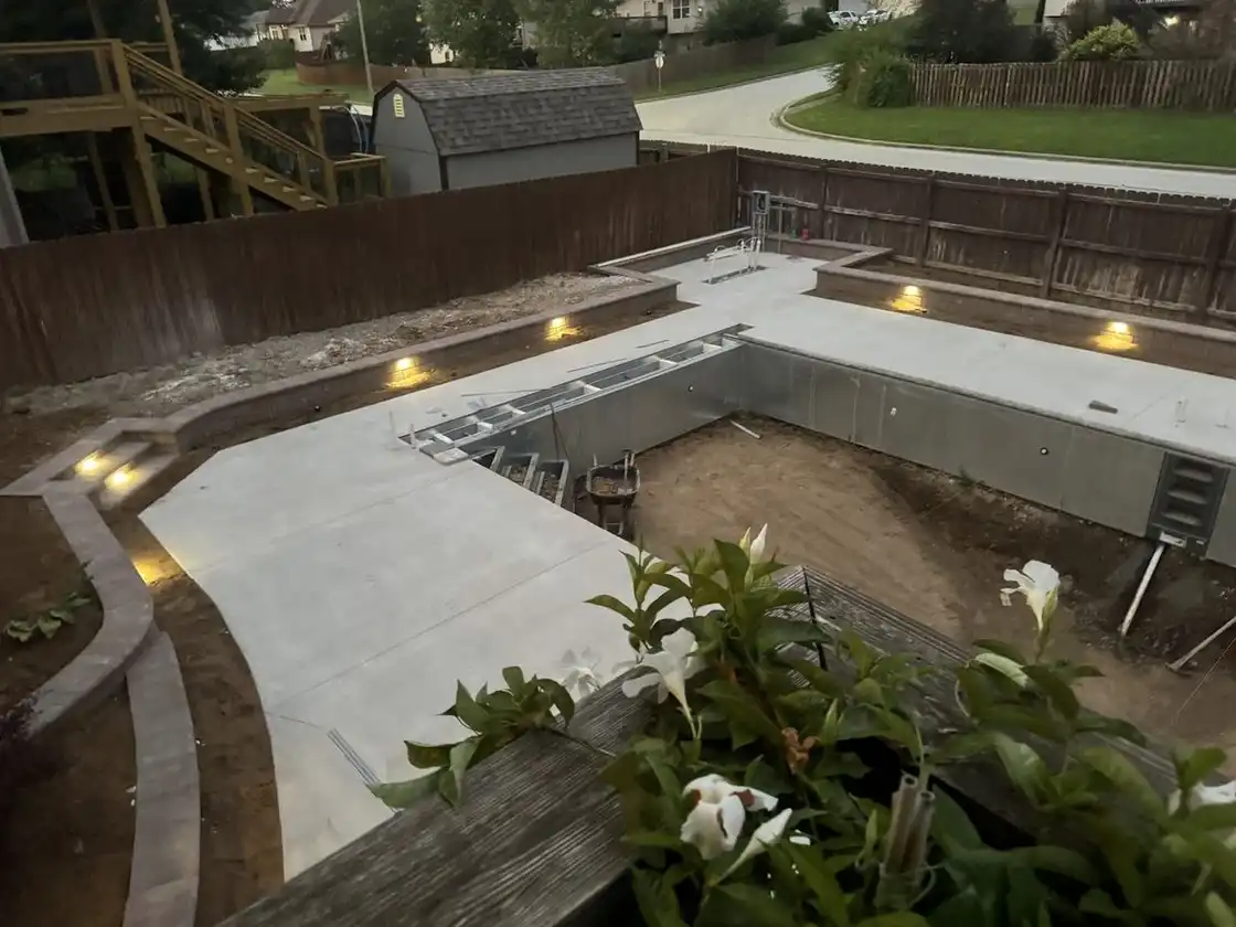Pool deck at dusk with lights set in the block planter walls, one of our jobs