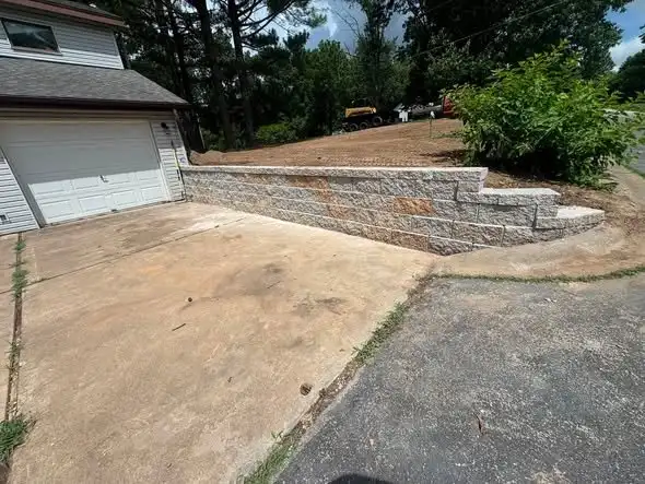 A block retaining wall along a driveway with steps built into the corner, one of our jobs