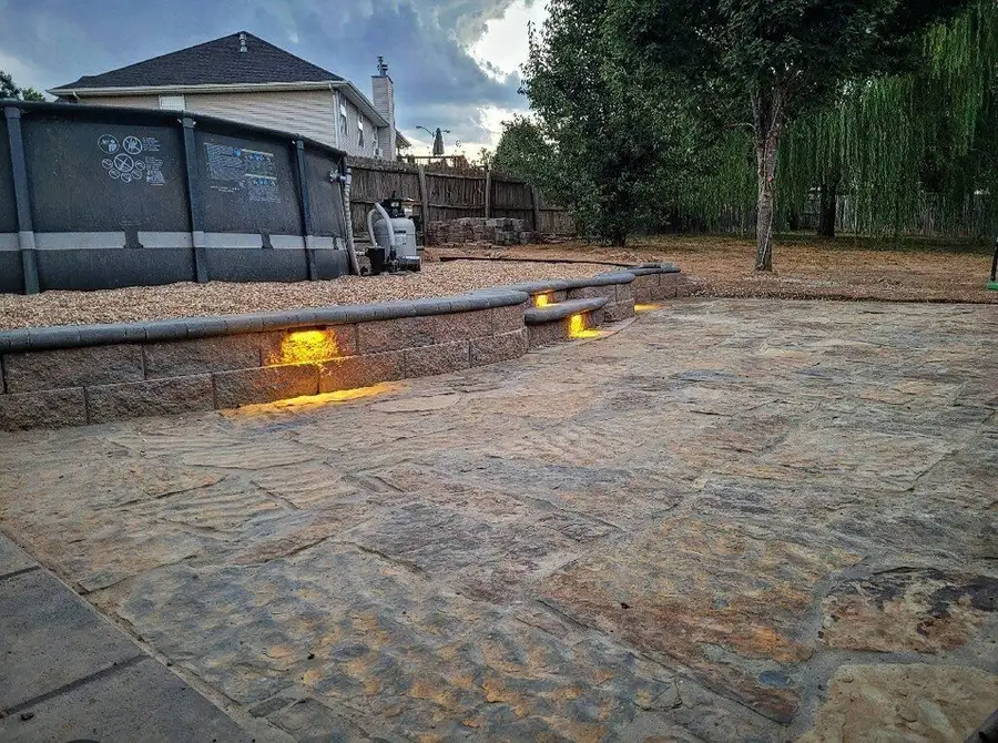 Stone patio with a lit seat wall