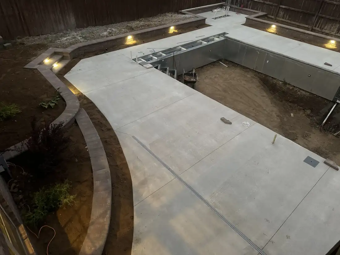 Concrete pool deck with lit block walls around an unfinished pool
